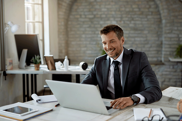 happy-male-entrepreneur-reading-email-laptop-while-working-office-600x400